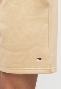 Μπεζ βαμβακερά σορτς με λεία υφή, που διαθέτουν ένα μικρό κόκκινο, λευκό και μπλε λογότυπο στο τελείωμα και αντίθετη ραφή κατά μήκος των άκρων.