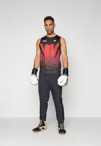 Boxing outfit featuring a sleeveless black and red gradient tank top, black pants, and black and tan shoes. White boxing gloves with black accents.