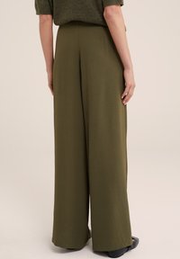Wide-leg trousers in olive green, made from a textured fabric. Features a high waist and a relaxed fit, with discreet pockets and a smooth waistband.