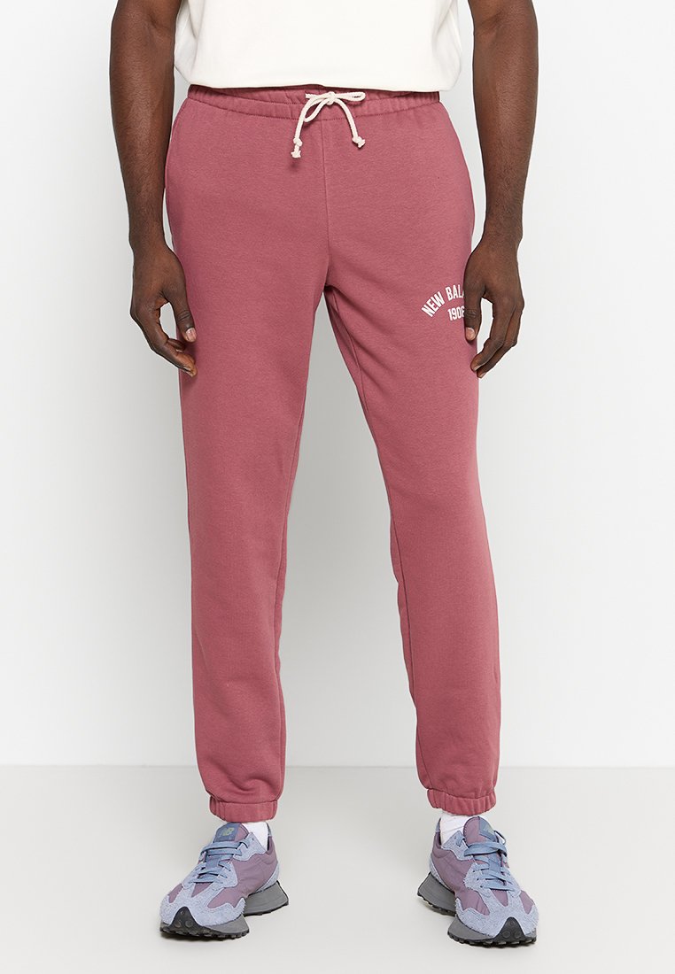 Rosa Sweatpants aus weichem Material, mit einem Kordelzugbund und einem weißen "New Balance"-Logo am linken Bein. Mit Bündchen an den Knöcheln.