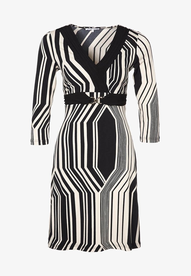 Robe longueur genou rayée géométrique en noir et blanc avec manches trois-quarts, col en V et ceinture noire avec une boucle argentée.
