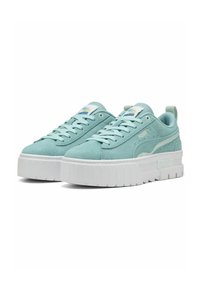 Világoskék velúr platform sneaker fehér gumitalppal; a nyelvén logóval és hátsó húzófüllel a könnyű felvétel érdekében.