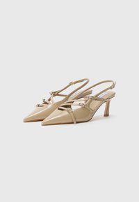 Tacchi slingback in pelle verniciata beige con punte affusolate, cinturini decorativi e tacchi alti sottili. Presentano dettagli con fibbie argentate.
