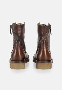 Bottines en cuir marron avec une finition texturée, dotées de fermetures éclair latérales doubles et d'une semelle cylindrique en caoutchouc de couleur claire.