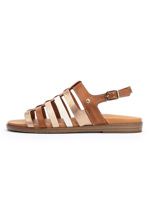 Sandal de cuero marrón con múltiples tiras de colores, incluyendo acentos en dorado y blanco. Presenta una correa ajustable en el tobillo y una suela plana.