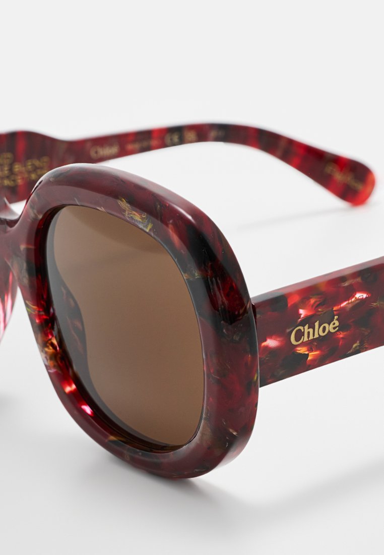Sonnenbrille aus Schildpatt mit großen runden Gläsern, braunem Farbton und goldener Logoakzentuierung. Dicke Rahmen mit rotem und braunem Marmoriertes Design.