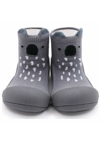 Calcetines grises suaves con suela de goma texturizada, que presentan un diseño de koala, incluyendo orejas, una nariz y manchas blancas en el cuerpo.
