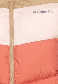 Puffjacka med en horisontell färgblockdesign: ljus tan, mjuk rosa och korall. Har en guldfärgad dragkedja och Columbia-logotyp. Slät textur.