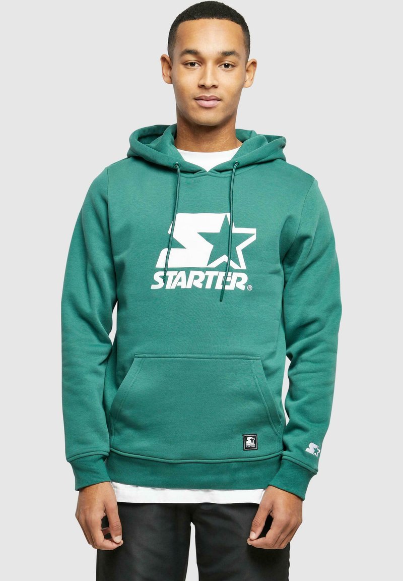 Zielona bluza z kapturem z dużym białym logo "STARTER" oraz wzorem gwiazdy na klatce piersiowej, z kieszenią z przodu i ściągaczami przy rękawach.