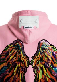 Sudadera con capucha rosa que presenta grandes diseños de alas de lentejuelas coloridas en el frente, con un tejido texturizado y una etiqueta de marca blanca en el cuello.