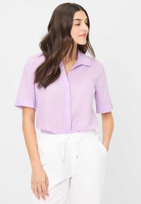 Lichtpaarse shirt met korte mouwen en geknoopte kraag, voorzien van een knoopsluiting aan de voorkant en opgerolde manchetten. Gladde, lichte stof.