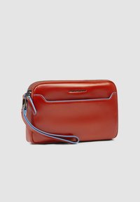 Rotes Lederportemonnaie mit glatter Textur, blauen Akzenten, Reißverschluss und Handgelenkriemen. Es verfügt über eine Fronttasche mit eingraviertem Logo.