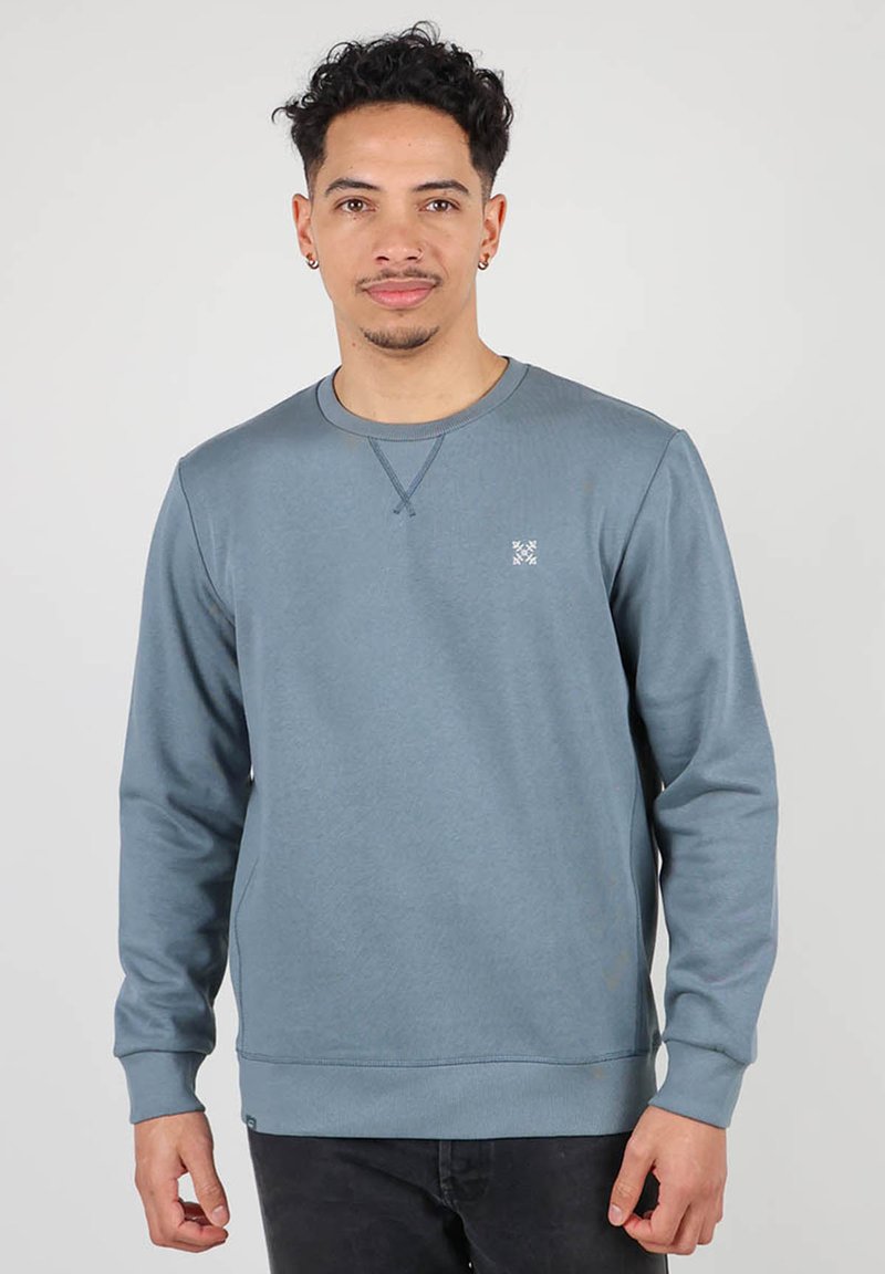 Sweatshirt bleu à manches longues, col rond et coupe ajustée. Présente un petit logo sur la poitrine ainsi que des poignets et un ourlet côtelés. Texture lisse.