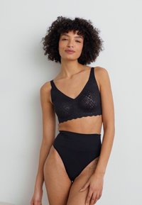 Black lace bralette with soft textured pattern and scalloped edges, paired with high-waisted black briefs, both in a smooth fabric.