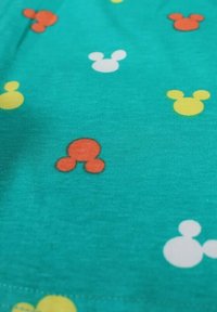 Un tissu turquoise à la texture lisse est parsemé de pois blancs, jaunes, rouges et oranges, ressemblant à des silhouettes de Mickey Mouse.