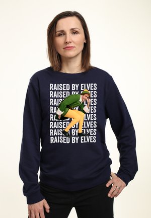 Granatowy sweter crewneck z kolorową grafiką postaci w zielonym i żółtym, z powtarzającym się tekstem "RAISED BY ELVES" w białym kolorze.