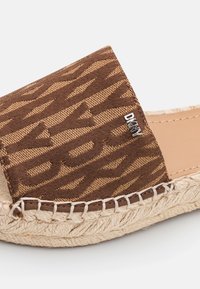 Brown slip-on espadrille with woven pattern, braided jute sole, and small silver DKNY logo on the upper strap.