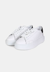 Baskets en cuir blanc avec un empiècement au talon en cuir noir, dotées d'une grosse semelle blanche, d'un bout arrondi et de lacets plats. Détails de couture simples.