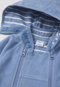 Lichtblauwe fleece jas met een gestreepte blauwe binnenkap, voorzien van twee voorritsen en een drukknoopsluiting voor een veilige pasvorm.