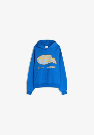 Haut à capuche bleu en coton avec une poche avant. Présente un texte graphique jaune "Still Moving" et "Never Loud Always Present."