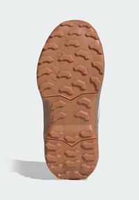 Pryžová podrážka boty s drsným vzorkem. Texturovaný povrch světle hnědé barvy, vybavený výraznými výstupky pro lepší trakci.