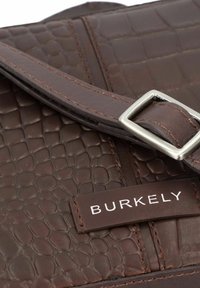Borsa a tracolla in pelle marrone con una texture a motivo coccodrillo, dotata di una fibbia in metallo argentato e di un'etichetta del marchio cucita che recita "BURKELY."
