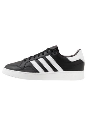Sneaker in pelle nera con dettagli bianchi, dotato di tre strisce bianche, design con lacci e suola testurizzata. Logo del marchio sulla parte posteriore.