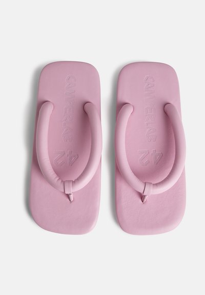 Tongs roses avec une semelle plate et des bretelles rembourrées. Les bretelles sont lisses et rondes, avec un texte de marque en relief sur le semelle.
