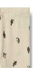 Beigefarbener Stoff mit kleinen, verstreuten Pinguinmustern in Schwarz und Braun, der eine weiche Textur und einen elastischen Bund aufweist.