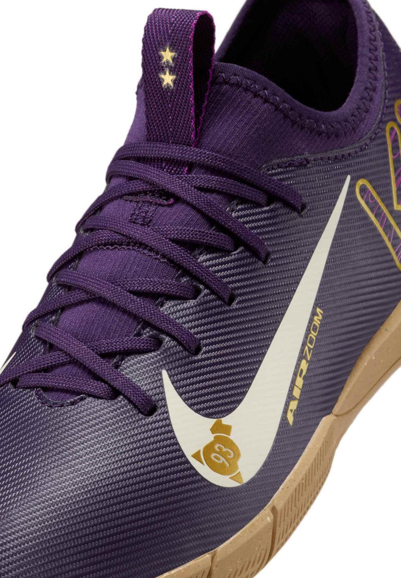 Zapatilla deportiva púrpura con parte superior texturizada, logo Swoosh blanco, acentos dorados y suela de goma marrón. Cuenta con cordones y una lengüeta.