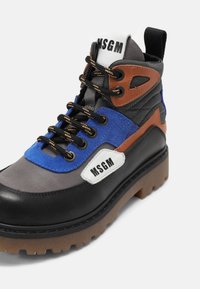 Bottes montantes en cuir et nubuck noir et gris avec des accents bleus et marron, semelle en caoutchouc et lacets noirs. Présente un logo blanc sur le côté.