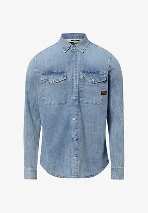 Jasnoniebieska dżinsowa koszula z długim rękawem, zapinana na guziki, z dwiema kieszeniami na piersi zapinanymi na guziki oraz z logo marki na prawej kieszeni.