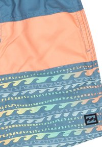 Costume da bagno in teal, pesca e azzurro chiaro con motivi a onda e un piccolo logo nero. Realizzati in materiale leggero e a rapida asciugatura.