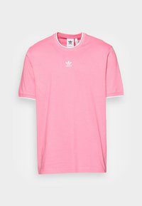 T-shirt Adidas rosa con logo bianco centrato sotto il collo, con bordi bianchi su collo e maniche, disteso su uno sfondo chiaro.