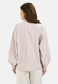 Striped blouse in cream and burgundy, featuring a relaxed fit, puffed sleeves, and buttoned cuffs, made from lightweight fabric.