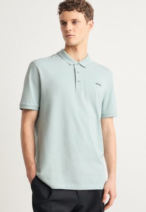 Polo léger vert menthe en tissu respirant, avec un col classique, une patte de boutonnage à trois boutons et un accent logo discret sur la poitrine.