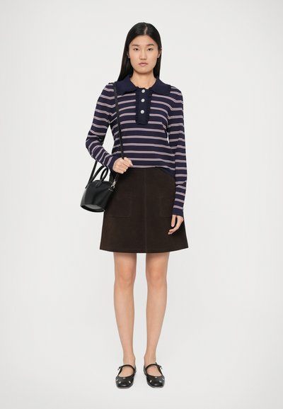 Top a righe blu navy e crema con maniche lunghe, caratterizzato da un colletto arricciato e tre bottoni; abbinato a una gonna A-line in suede marrone e una borsa nera.