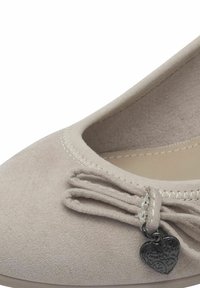 Ballerine beige realizzate in morbido tessuto, con un dettaglio a fiocco e un piccolo charm a forma di cuore, e cuciture sottili lungo il bordo. Design con punta arrotondata.