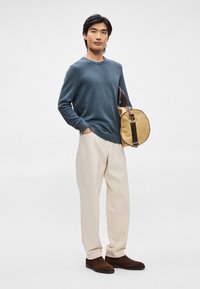 Blå teksturert langermet skjorte, kremfargede bukser, brune semskede sko, og en beige rund veske med mørkebrune accenter.