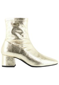 Zlaté metalické kotníkové boty s špičatou špičkou, hladkým povrchem a blokovým podpatkem. Obsahují malou logo destičku poblíž kotníku.