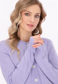 Lavender knitted cardigan with long sleeves, round neckline, and buttons. Features ribbed detailing and soft, fluffy texture.