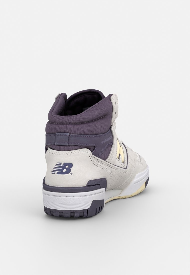 Sneaker alta in suede grigio chiaro con accenti viola. Presenta un colletto imbottito, dettagli con logo e una suola in gomma testurizzata.