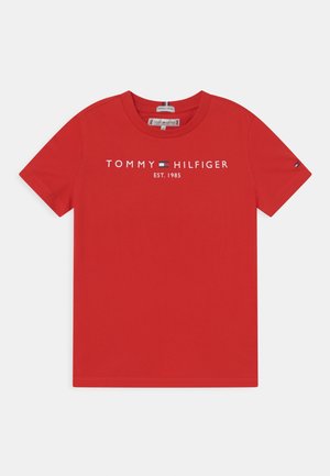 T-shirt in cotone rosso con collo a giro, maniche corte e la scritta "TOMMY HILFIGER EST. 1985" stampata in bianco sul petto, accompagnata da un emblema blu e bianco.