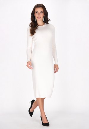 Knit, long-sleeve, cream dress with a fitted silhouette and subtle ribbing, featuring button accents at the cuff and a mid-calf length.