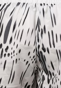 Black and white patterned fabric showcasing abstract lines and dots with a smooth texture, featuring an elastic waistband at the top.