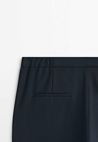 Navy blue trousers featuring a smooth texture, an elastic waistband, and a single back pocket with a concealed seam detail.