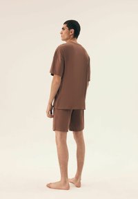 Loose-fitting brown short-sleeve shirt and matching shorts made of soft fabric. The outfit features a casual design with no visible patterns.