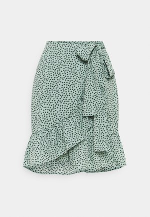 Jupe vert menthe avec un motif à pois, ourlet volanté et un lien à la taille. Fabriquée en tissu léger pour un design fluide.