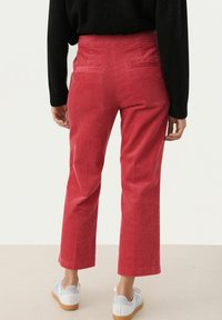 Rode corduroy broek met rechte pijpen, voorzien van subtiele verticale strepen, achterzakken en een hoge taille.