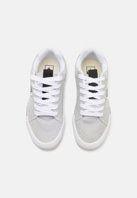 Sneakers din suede gri, cu vârf jos, șireturi albe, talpă din cauciuc și accente negre. Include guler căptușit și patch cu logo pe limbă.